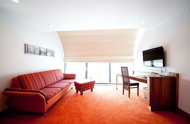 Hotel Ambio Zimmer mit großer Couch, einem Schreibtisch mit Sessel.